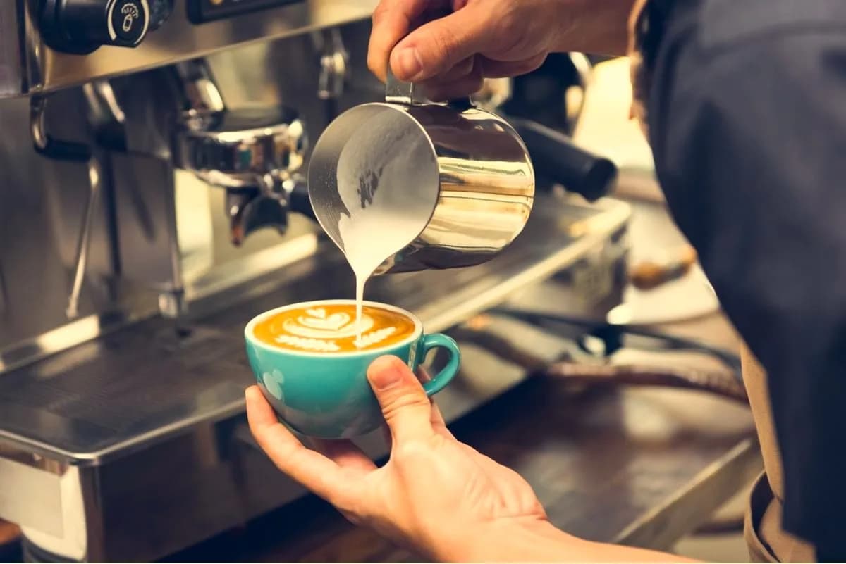 Barista pouring latte art into a cup